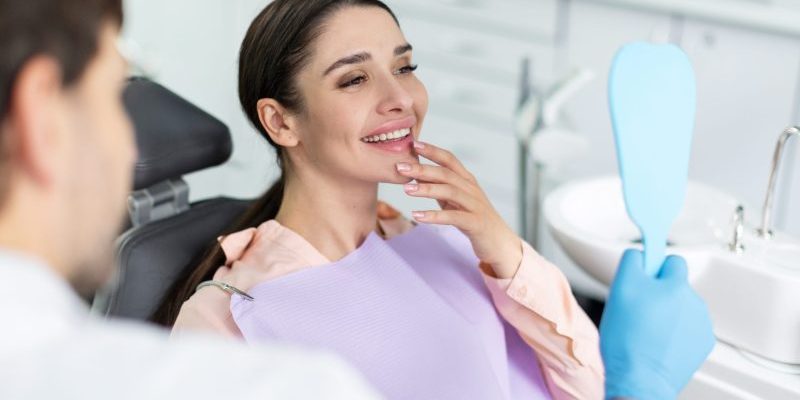 Smiling,Woman,Looking,In,Mirror,After,Dental,Procedure,In,Clinic, restorative dentist taylorsville